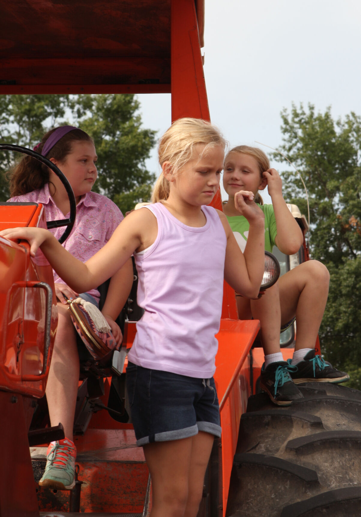 Anna, Haley and Megan Hilkerbaumer sit on a tractor